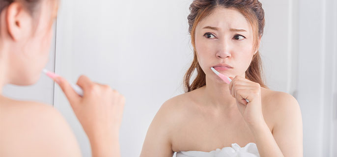 鏡を見ながら歯を磨いている女性