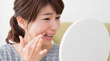 鏡を見ながら歯並びを確認してる女性