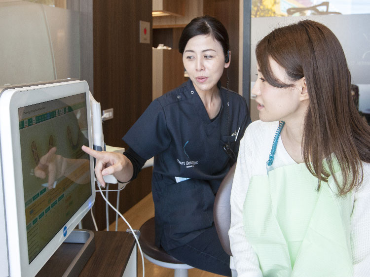 タブレットを使って保定期間について説明している男性歯科医師